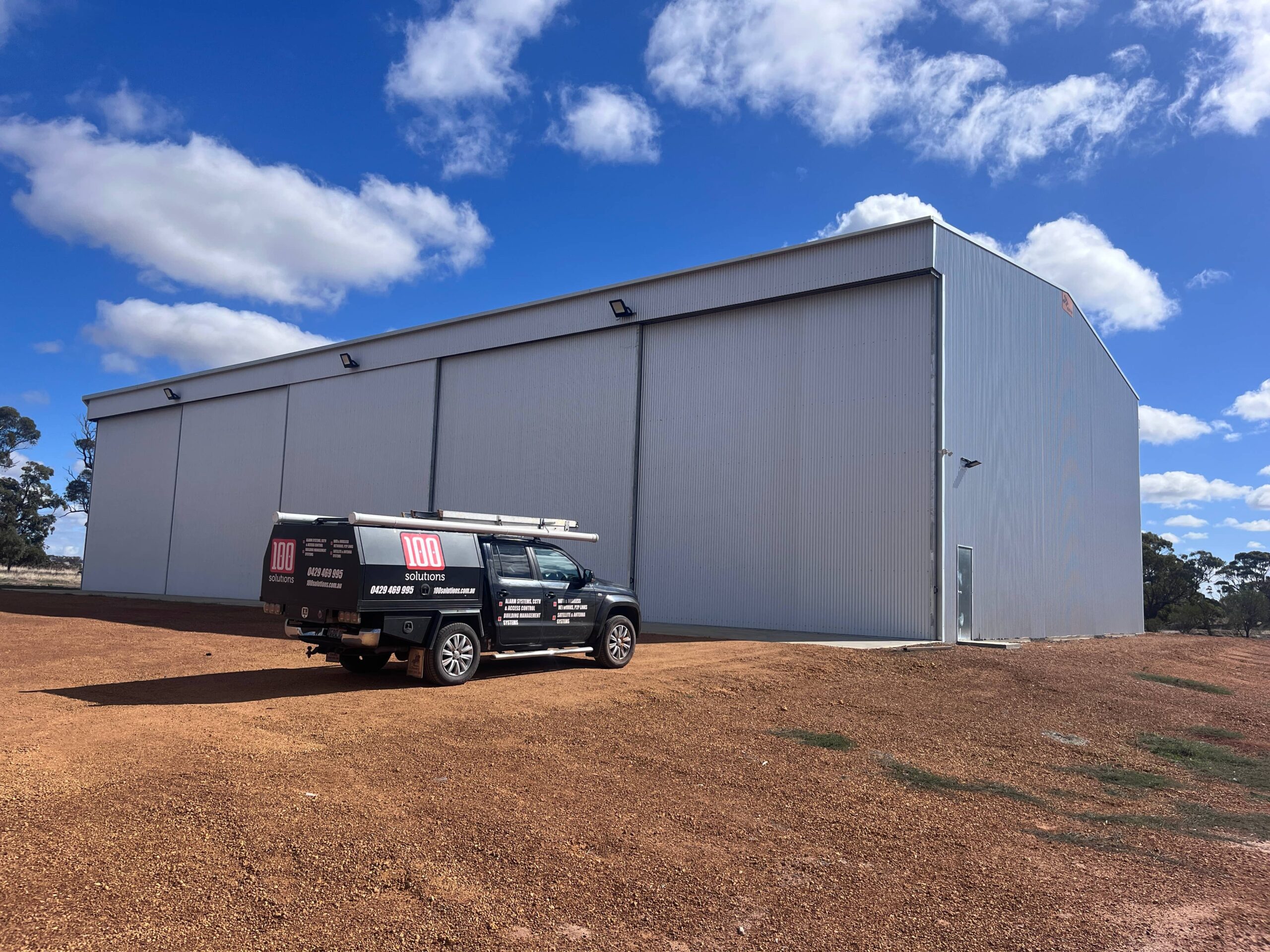 100 solutions security vehicle parked outside a grey industrial building for Farm agriculture security services.